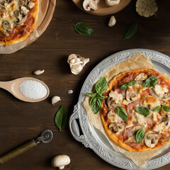 Flat lay with homemade italian pizza, olive oil, tomatoes and cheese on wooden brown table