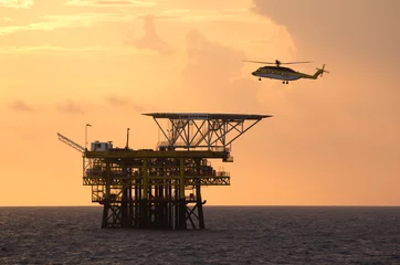 Schilderijen op glas A helicopter on top of a offshore oil-platform transporting roughnecks  © corlaffra