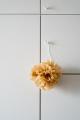 handmade brown paper pom pom hanging in a room cabinet door. Minimalism concept if interior design. Kid's, girl's room.