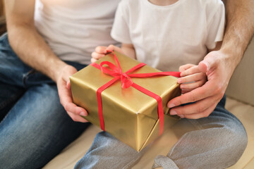 Father and daughter. Handsome young man gives a gift or present in a box to little cute girl at home, have fun. Dad and child laugh. Father's day. Happy birthday!