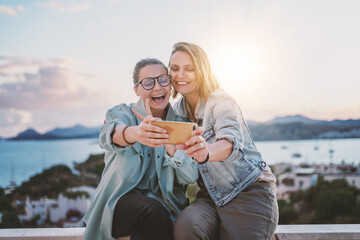 Carefree joyful young woman taking selfie on summer day