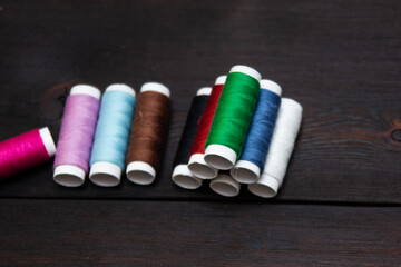 Colored threads on a wooden background. Sewing concept.