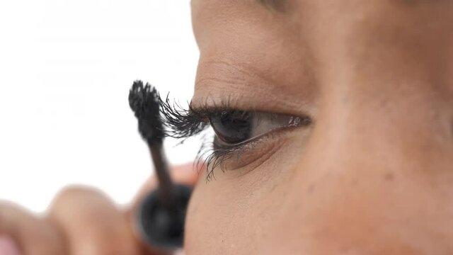 Close-up of a woman applying mascara on eyelashes. Beauty concept. Isolated, on white background