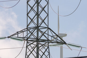 Close up of modern electric post and wind turbine in the background.