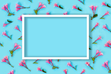 Fototapeta na wymiar Beautiful pink weigela flowers on blue paper background. Trendy creative backdrop.