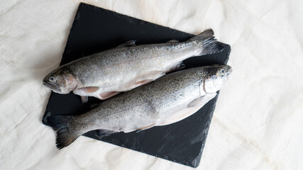 two gutted rainbow trout fish on a black stone board. fish prepared for soup. fish soup ingredient. gutting the fish