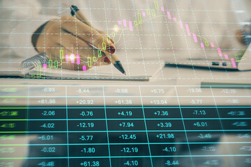 Double exposure of woman's hands making notes with forex graph hologram. Concept technical analysis.