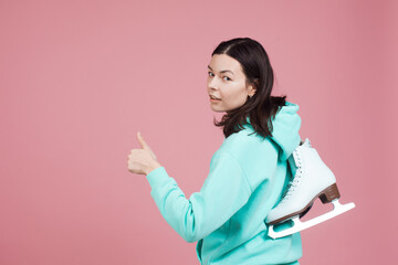 Figure skating, Hobbies and a healthy active lifestyle. A cheerful girl in a bright hoodie with skates on her shoulder