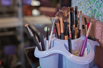 Professional visagiste brushes aisle in makeup studio. Set of a cosmetic brushes . Professional visage brushes for face makeup on table.Body art paint in beauty salon.Close up brush kit .