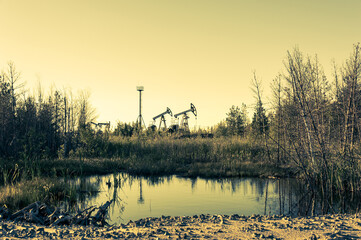 Oil pump rig. Oil and gas production. Oilfield site. Pump Jack are running. Drilling derricks for...