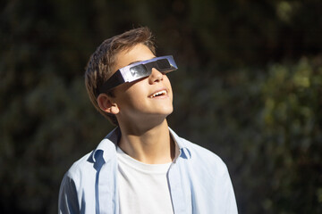 teenager watching an eclipse of the sun with eclipse glasses - obrazy, fototapety, plakaty