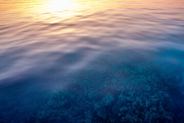 Stunning seascape on coral under clear water. Sunset with a reflection in the water taken with slow shutter. Soft Focus due to Slow Shutter. Speed Meditation. No people. Sun line. Romantic journey.