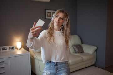 funny girl with a phone and big headphones takes a photo on her smartphone.