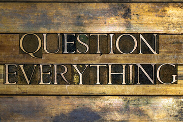 Photo of real authentic typeset letters forming Question Everything text on vintage textured silver...