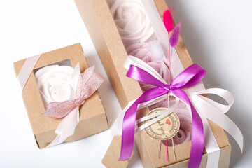 Marshmallows in craft paper packaging. Decorated with ribbons and dried flowers. Zephyr in the form of a rose. On white background.