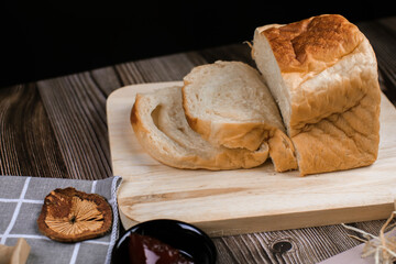 Fresh homemade loafs bread and sliced bread on cutting board with jam strawberry close up on wooden background.Healthy Diet.Prepared from a dough of flour and water, usually by baking.