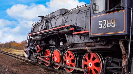 Retro steam train rides by rail on the blue sky background. Railway worker's day
