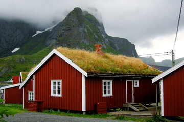 Fototapeta na wymiar Reine, Lofoten Islands, Norway. House with traditional grass roof in Reine, with mountain in mist in the background.