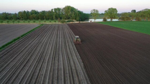 A farmer plowing his field with a tractor during spring, seen from above with a drone.