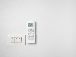 Remote controller of air condition and light switches on white wall.