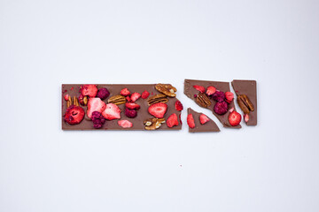 A broken chocolate bar with nuts and dried berries.