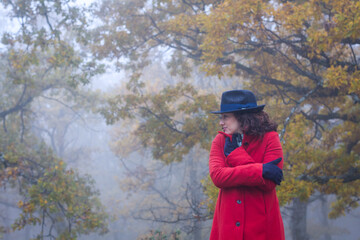 Horizontal view of misterious woman surrounded by scary autumn oak forest  in the fog waiting for someone.
