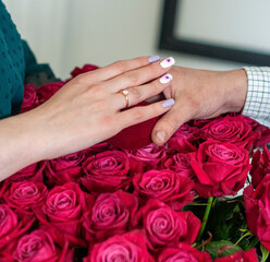 Obraz na płótnie Canvas Betrothal ring on woman hand with pink bouqet of roses. Romantic event.