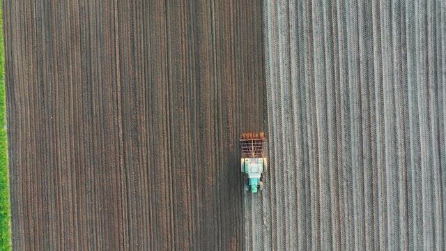 A farmer plowing his field with a tractor during spring, seen from above with a drone.