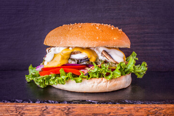 Craft vegetarian burger with mushrooms, cottage cheese, salsa sauce, fresh vegetables. For restaurant menu. Veggie beet on a board with a stone and wooden deck over wooden background