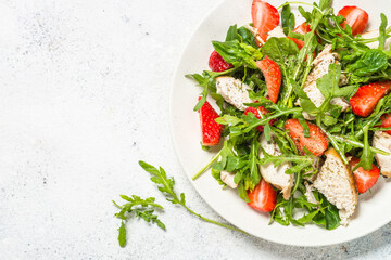 Green salad with chicken, strawberry and arugula.