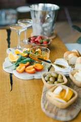 Snacks for an aperitif. Strawberries, cheese, olives, peach, oranges, bread, honey, champagne glasses and champagne in an ice bucket.