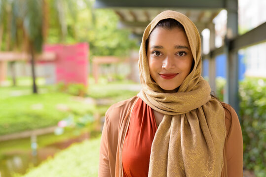 Face of young beautiful Indian Muslim woman at the park outdoors