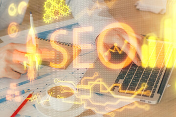 Multi exposure of seo icon with man working on computer on background. Concept of search engine optimization.
