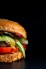 burger with chop, steak, cheese, salad on a black background