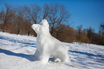 Fototapeta na wymiar The figure of the white dog cobbled from snow, sculpted snowman in the Park