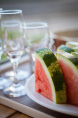Watermelon slices and wine glasses in the background