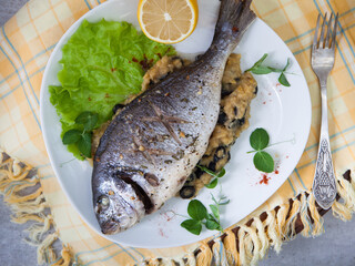 Grilled whole marinated fish on a plate with a side dish and serving
