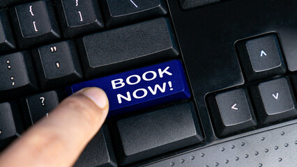 Hand press blue button computer keyboard with a word BOOK NOW!