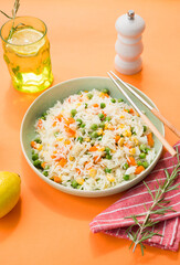 A plate of white rice with vegetables on a stylish trending orange background, Asian food