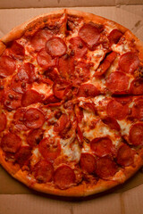Pizza. spicy pizza on a cardboard box. Tasty pizza with bacon, salami and cheese.Background pizza pepperoni.