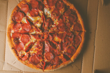 Pizza. spicy pizza on a cardboard box. Tasty pizza with bacon, salami and cheese.Background pizza pepperoni.Vintage photo processing