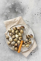 Quail eggs in a white plate on the kitchen table. Quail eggs m Corolla on a culinary background. Concept of preparation for baking. Top view with space for text