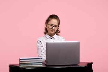 A young girl is studying on the Internet. The girl sitting at the table learns.