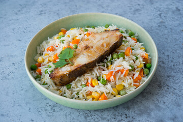 Close up Rice with vegetables and fish steak in a plate, selective focus