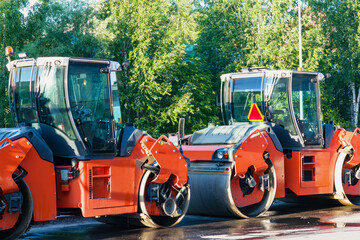 Orange road rollers for laying asphalt during construction, paving