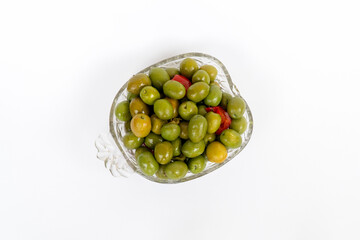 Marinated olives in small transparent bowl. On white background. Pickled green olives