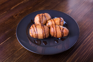 Deep fried bananas on plate over wooden table background. Tasty dessert from pan fried bananas in asian style