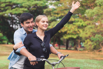 Fototapeta premium Happy young couple walking their bike along happily talking in park