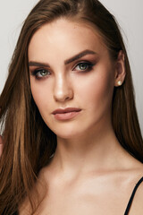 Naklejka premium Beautiful face of young woman with clean fresh skin close up isolated on the grey background. Beauty portrait. Perfect fresh skin. Pure beauty model. Youth and skin care concept