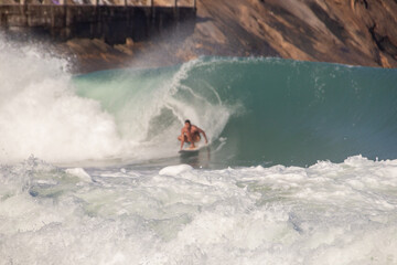 Naklejka premium white foam of a wave at leblon beach with defocused surfer in the background in Rio de Janeiro.